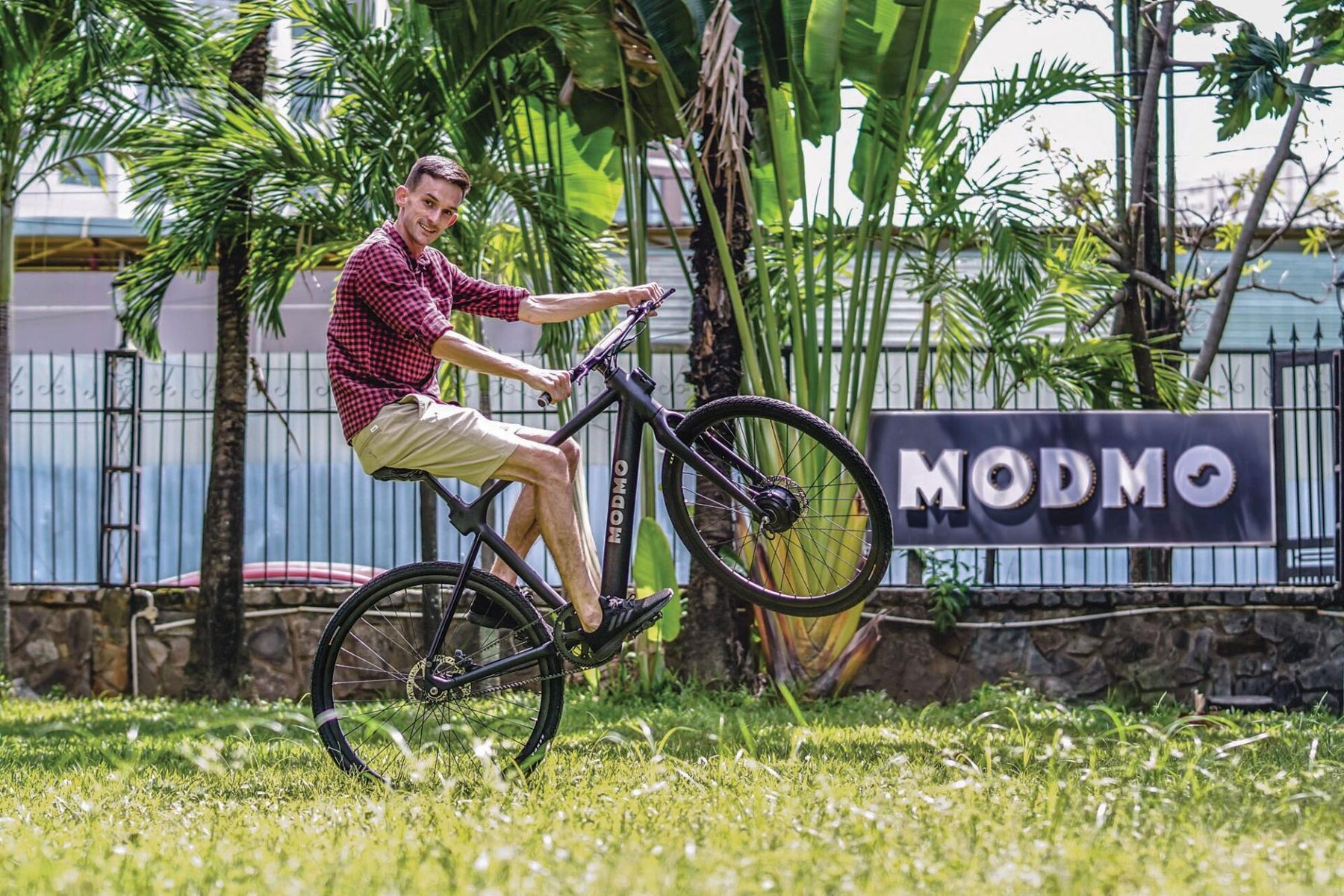 Jack pulling a wheelie on a Modmo in front of the MODMO sign, Ho Chi Minh City